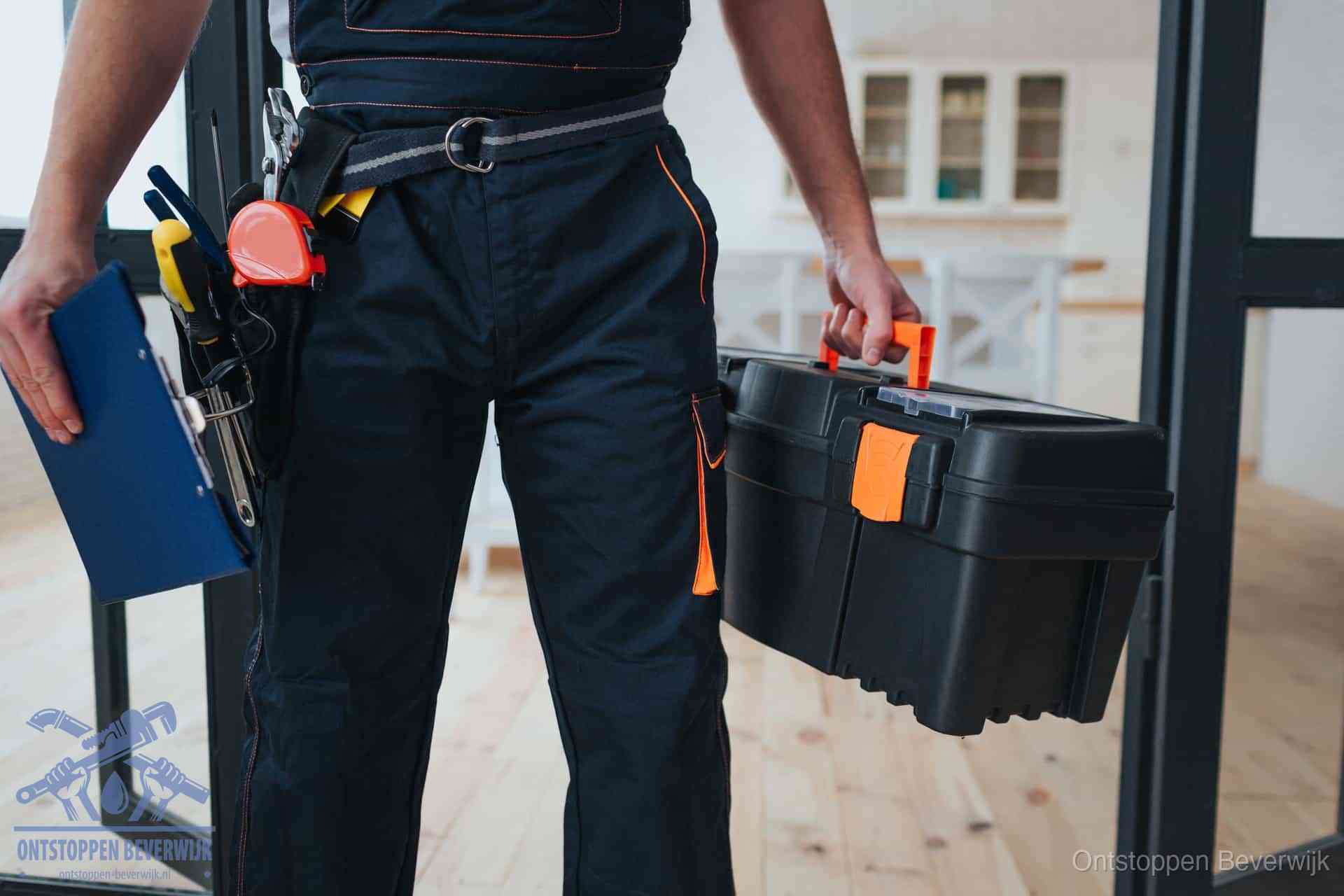 Een monteur met gereedschapsriem en klembord in een keuken, klaar om een transparante prijs voor het gootsteen ontstoppen in Beverwijk te geven
