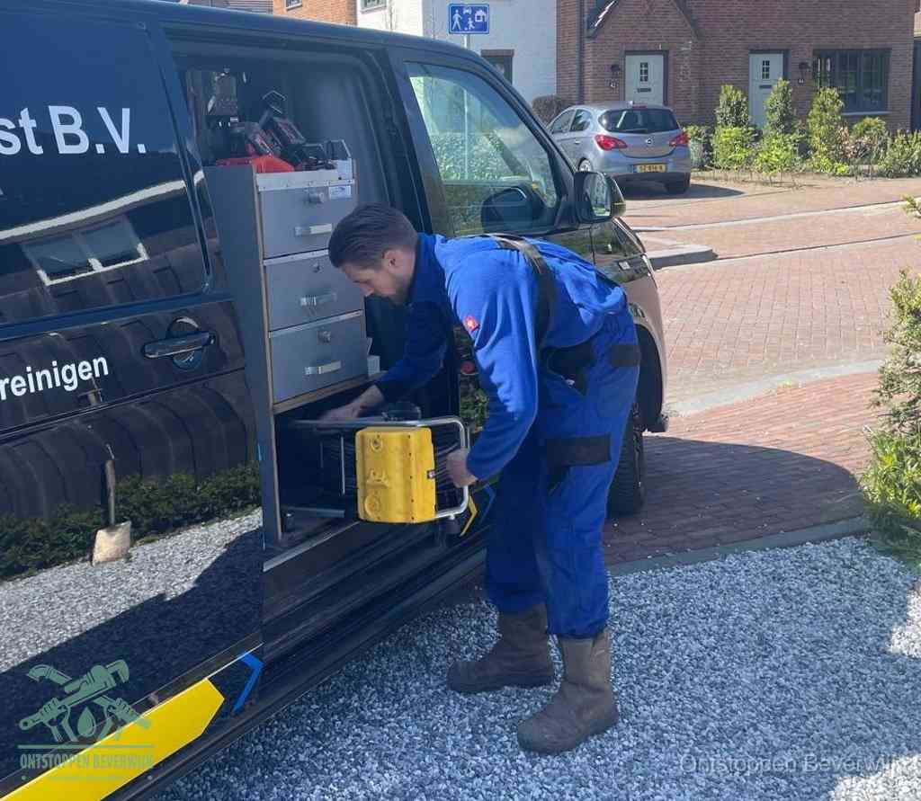 Een monteur pakt buiten op de oprit gereedschap uit de bedrijfsbus, het moment om een professional in te schakelen voor een verstopte afvoer in Beverwijk