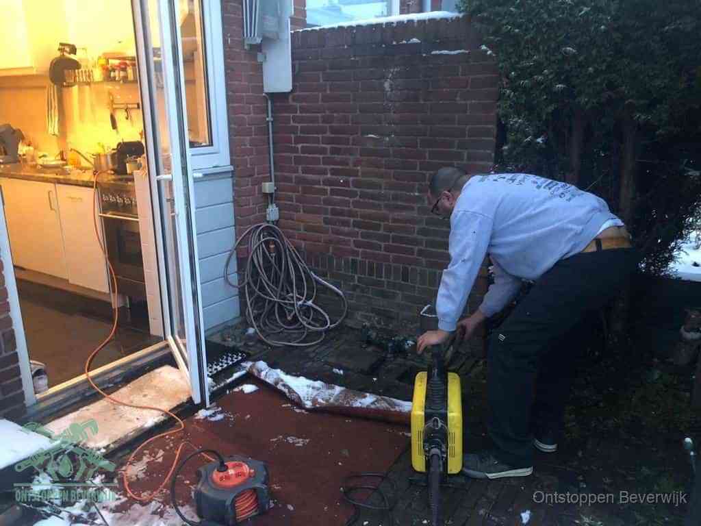 Een monteur werkt buiten bij een open riool-/grondput met een elektrische ontstoppingsmachine om een verborgen afvoerprobleem op te sporen in Beverwijk