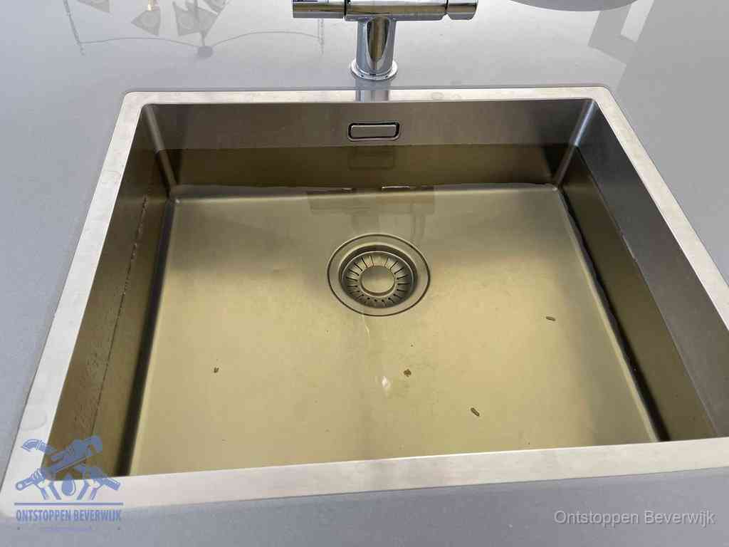 Stilstaand water in een rvs spoelbak dat niet wegloopt, een duidelijk signaal van een gootsteenverstopping in Beverwijk