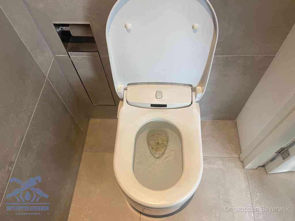 Een wit hangtoilet waarin een prop wc-papier op het water blijft drijven, een duidelijk signaal van een verstopte wc in Beverwijk