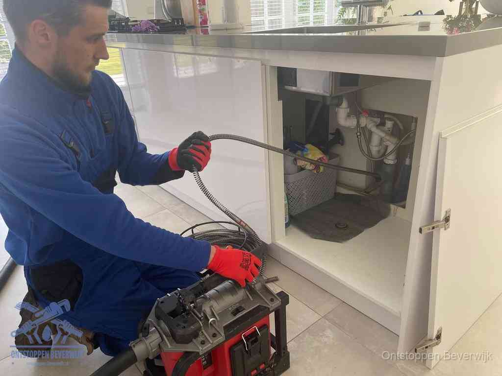 Een monteur reinigt de keukenafvoer grondig met een veermachine om terugkerende gootsteenverstoppingen te voorkomen in Beverwijk