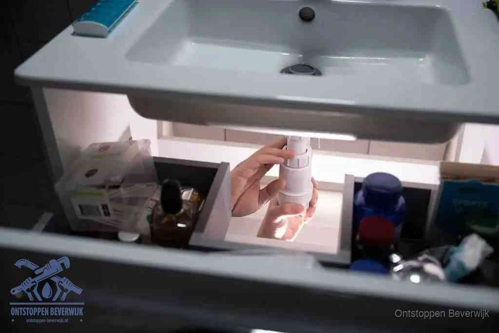 Een pompfles met zeep boven een wastafel in de toiletruimte, de warm water en afwasmiddel-methode om de wc te ontstoppen in Beverwijk