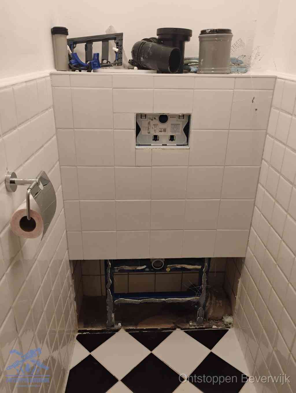 Een toiletruimte waar het hangtoilet en de inbouwreservoir-onderdelen zijn vrijgelegd voor onderhoud, periodiek nazicht voorkomt een wc-verstopping in Beverwijk