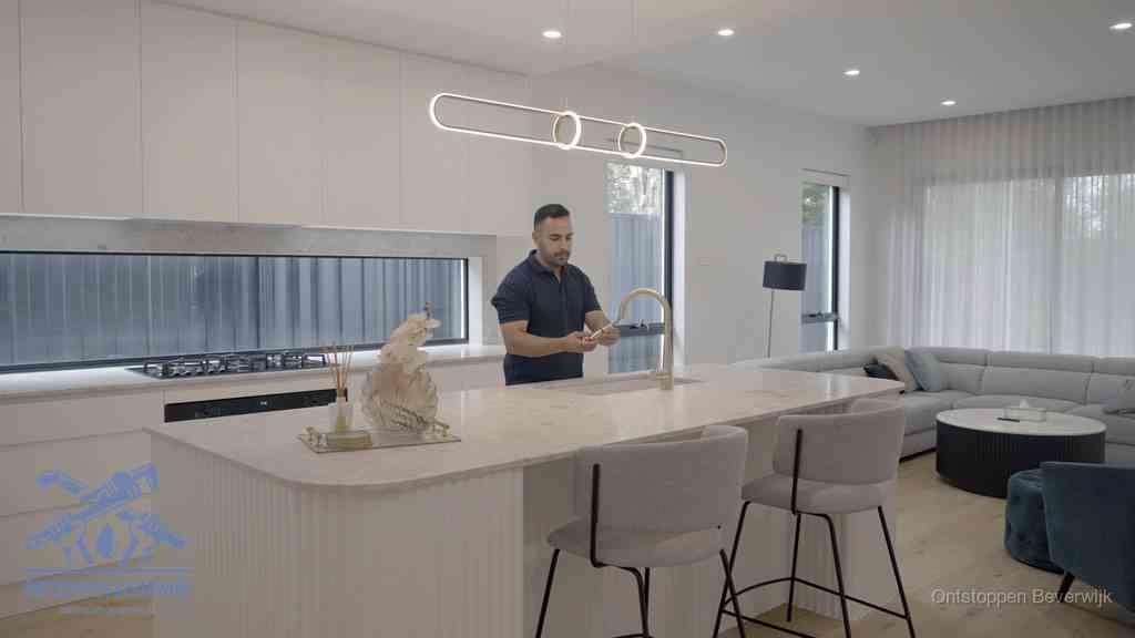 Een bewoner bij de keukenspoelbak die zelf aan de slag gaat met een verstopte gootsteen in Beverwijk